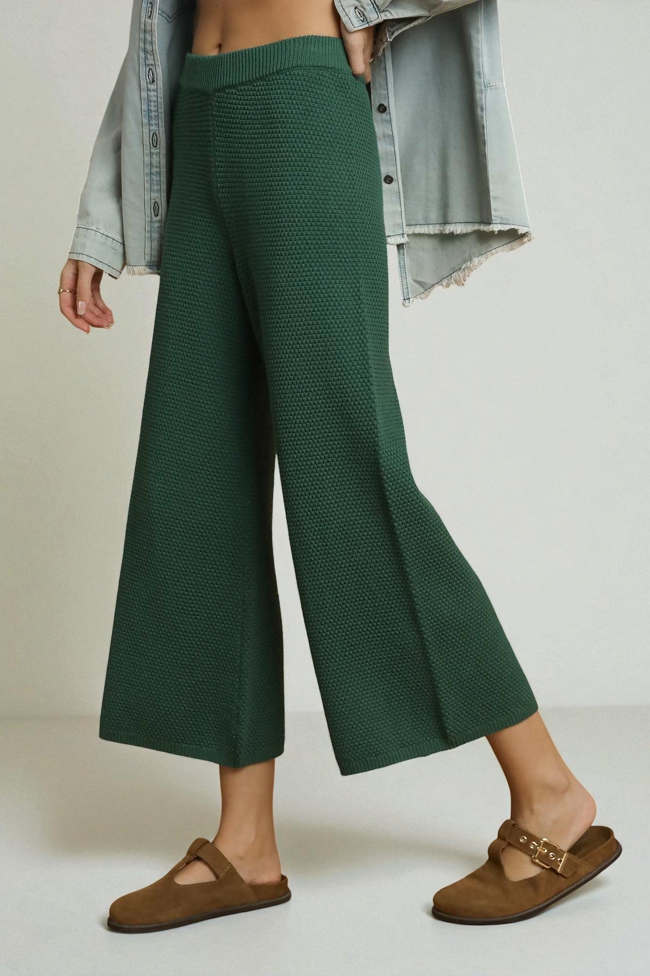 Person wearing green ribbed knit pants with a plain background