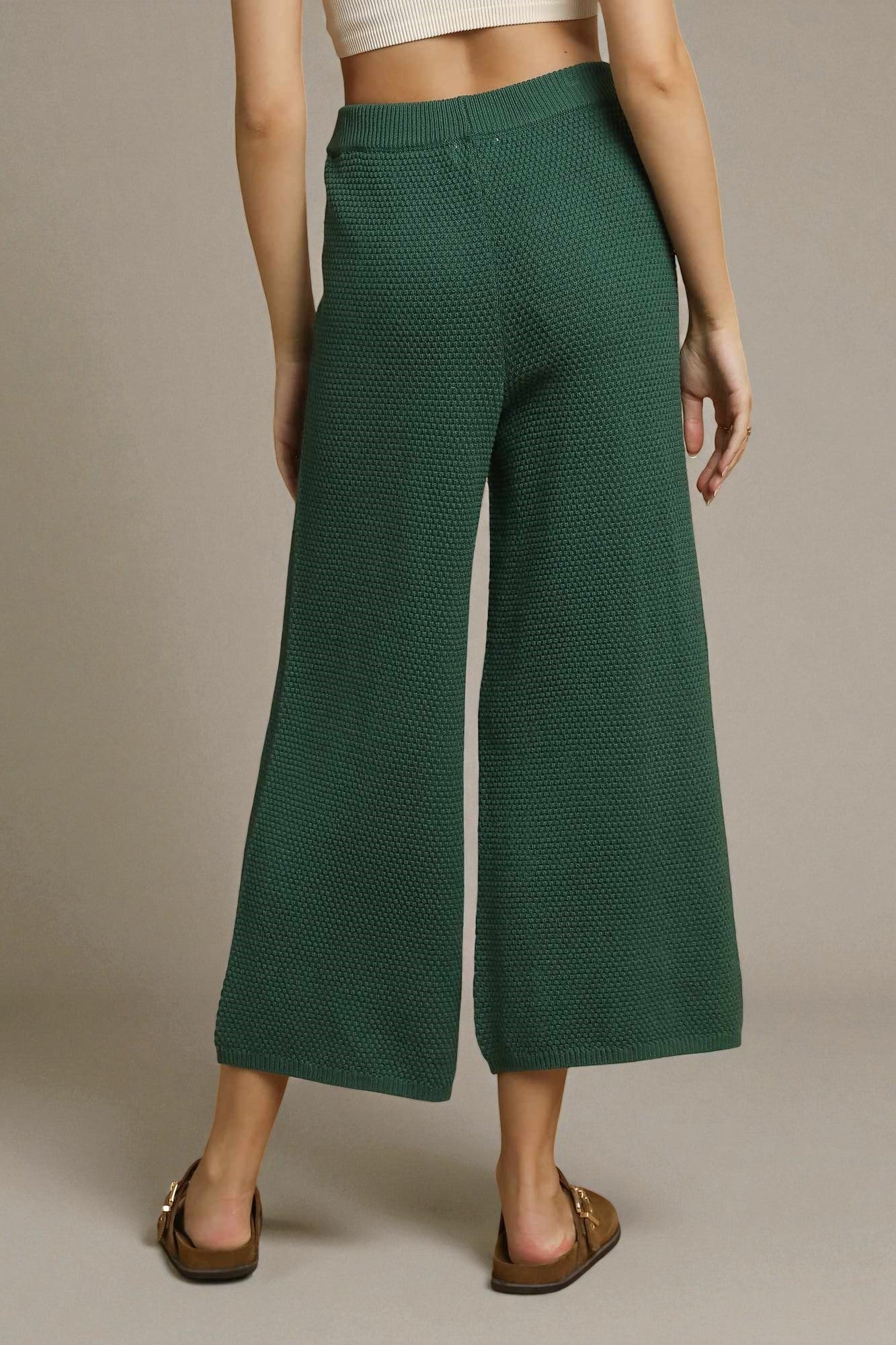 Green textured wide-leg pants worn by a person on a beige background