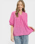 Woman wearing a pink blouse and blue jeans with a white background