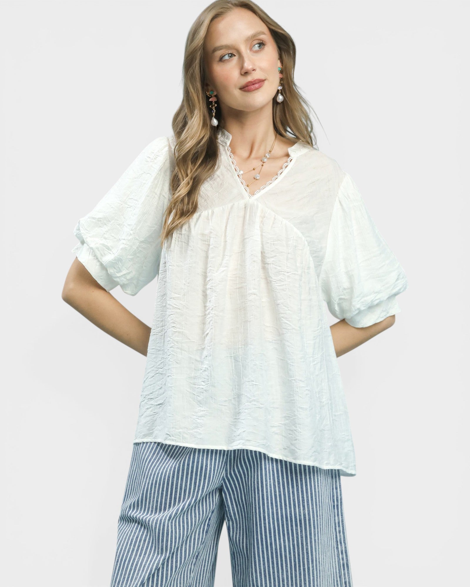 Woman wearing a light blue blouse and striped pants on a white background