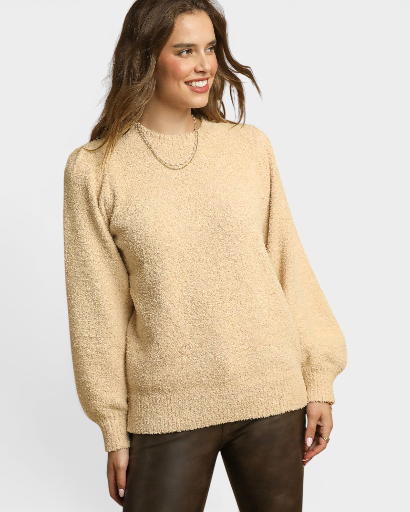 Woman wearing a beige sweater on a plain background