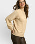 Woman wearing a beige sweater against a plain background