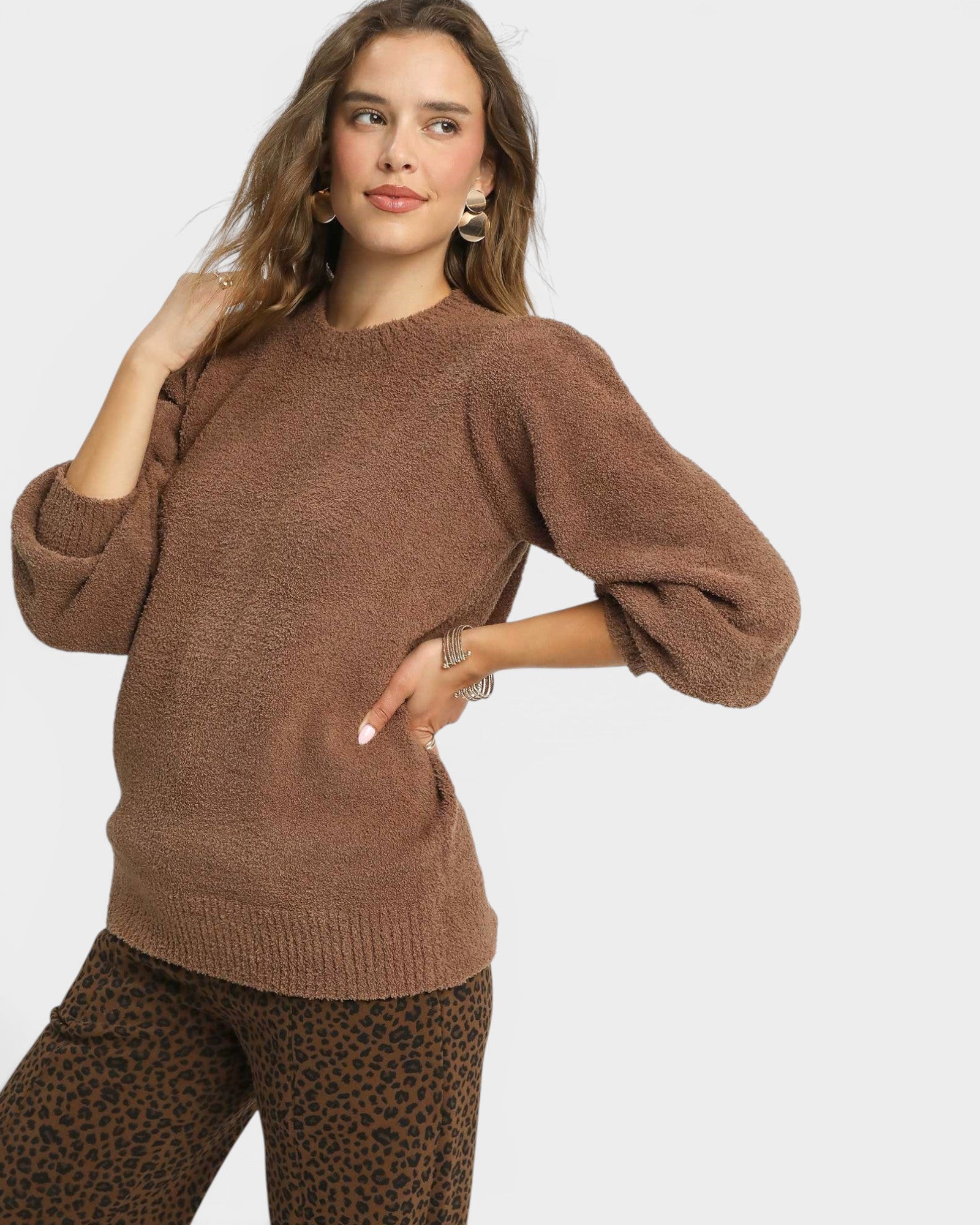 Woman wearing a brown sweater with a plain background