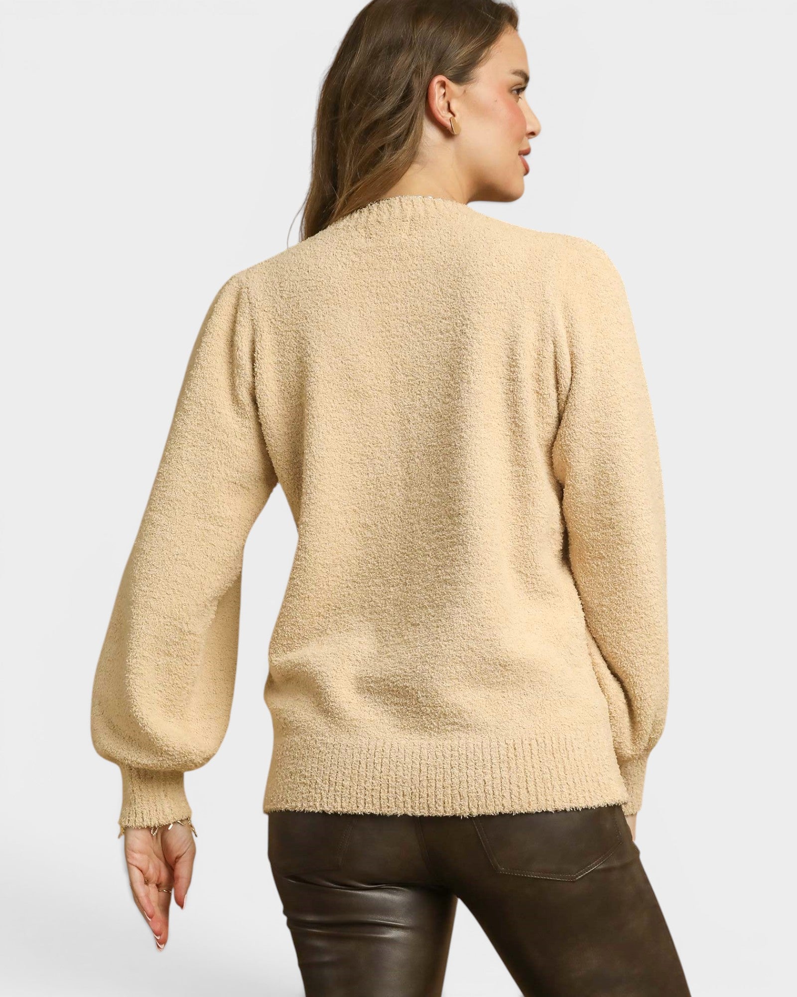 Woman wearing a beige sweater on a plain background