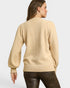 Woman wearing a beige sweater on a plain background