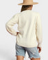 Person wearing a cream sweater and denim shorts with a beige hat on a light gray background
