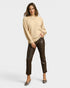 Woman wearing a beige sweater and brown leather pants on a white background