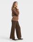 Woman wearing a brown sweater and leopard print pants on a white background