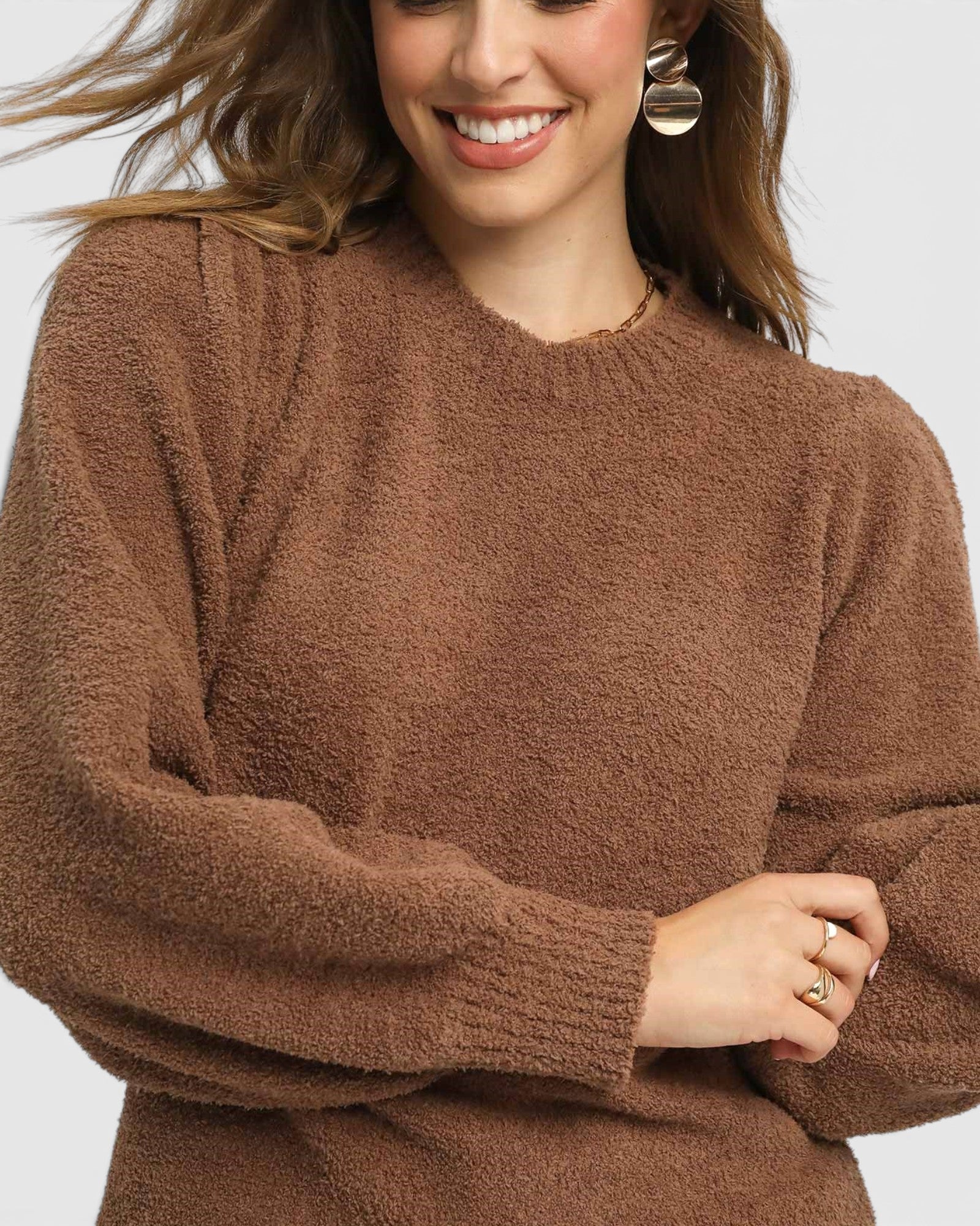 Woman wearing a brown sweater on a plain background