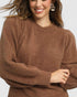 Woman wearing a brown sweater on a plain background