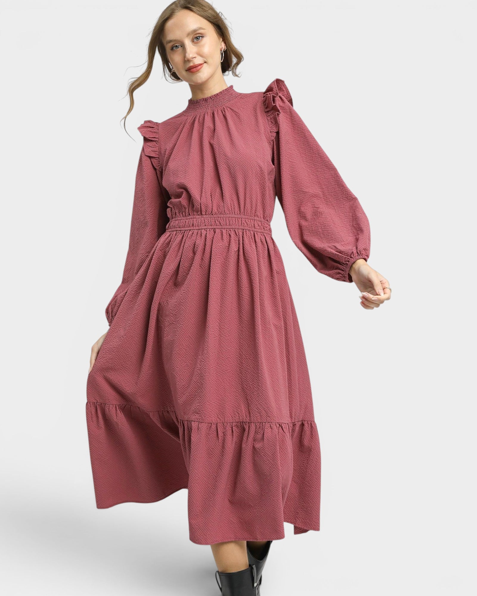 Woman wearing a pink dress with long sleeves on a white background