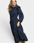 Woman wearing a navy blue dress with long sleeves and a belt on a white background