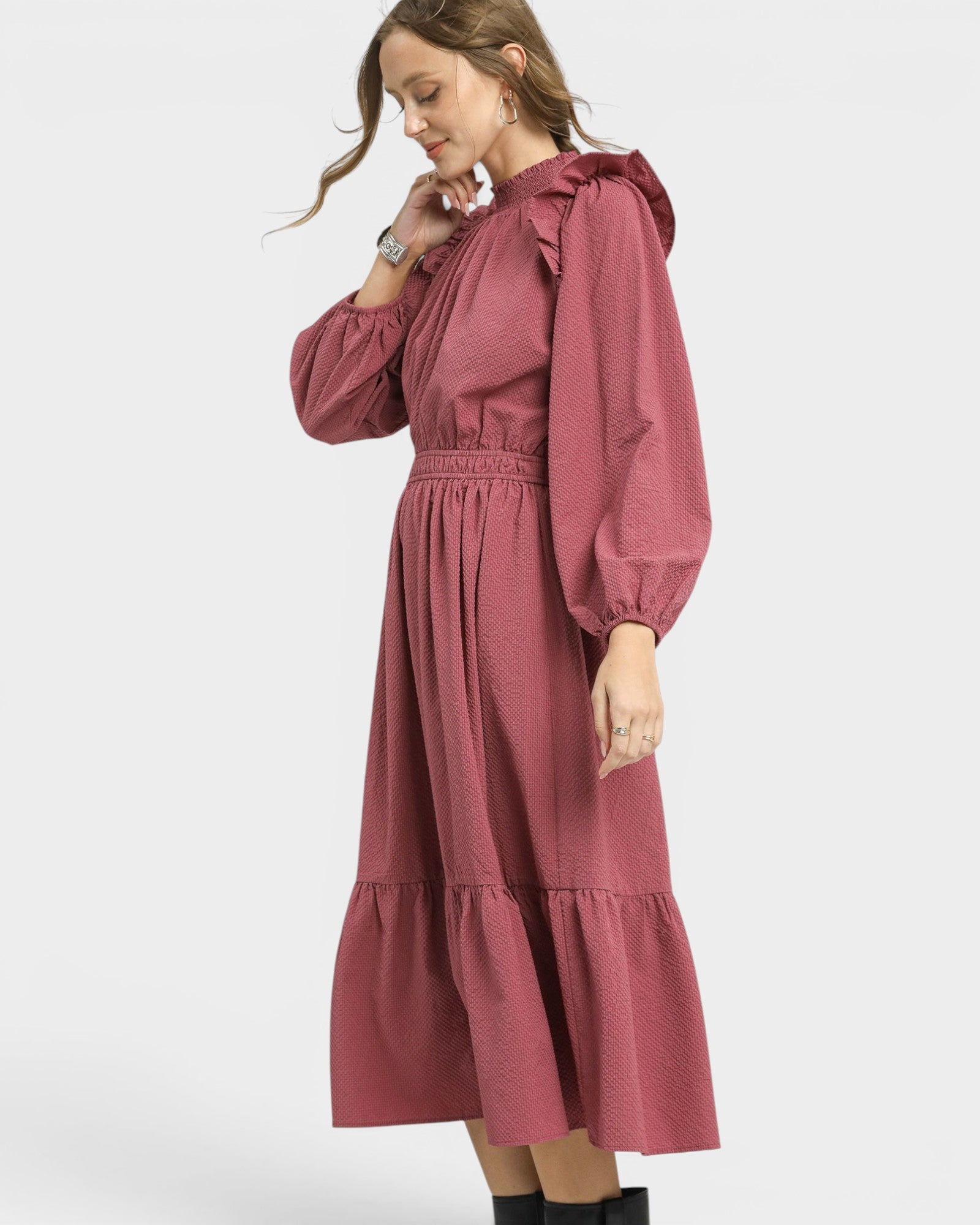 Woman wearing a burgundy dress with ruffled sleeves on a white background