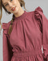 Woman wearing a pink dress with ruffled sleeves against a gray background