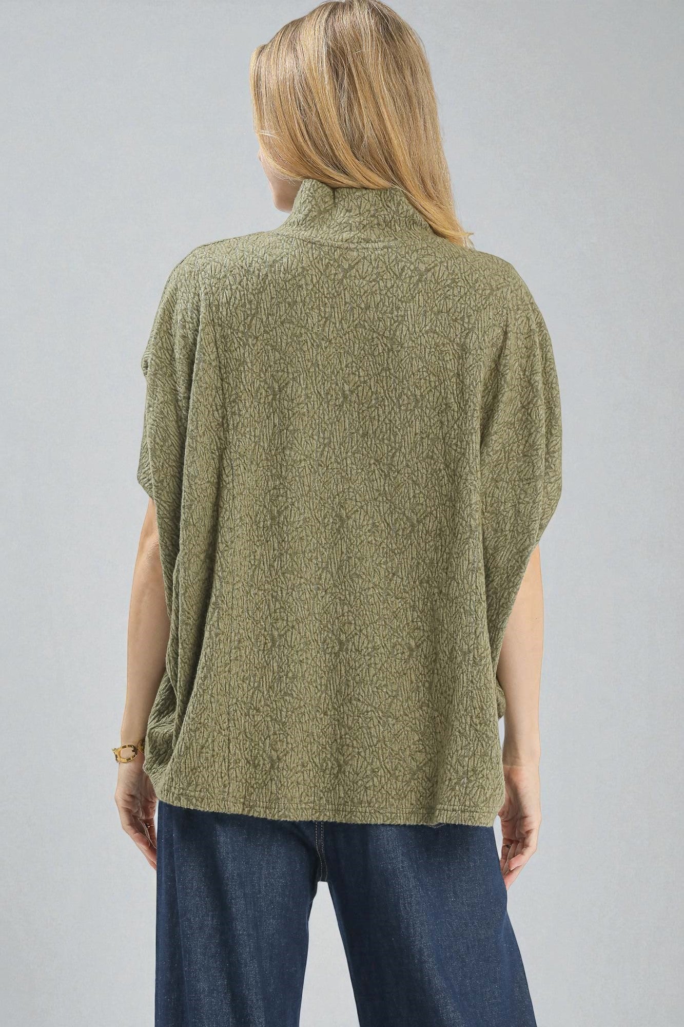 Person wearing a green knitted vest on a gray background