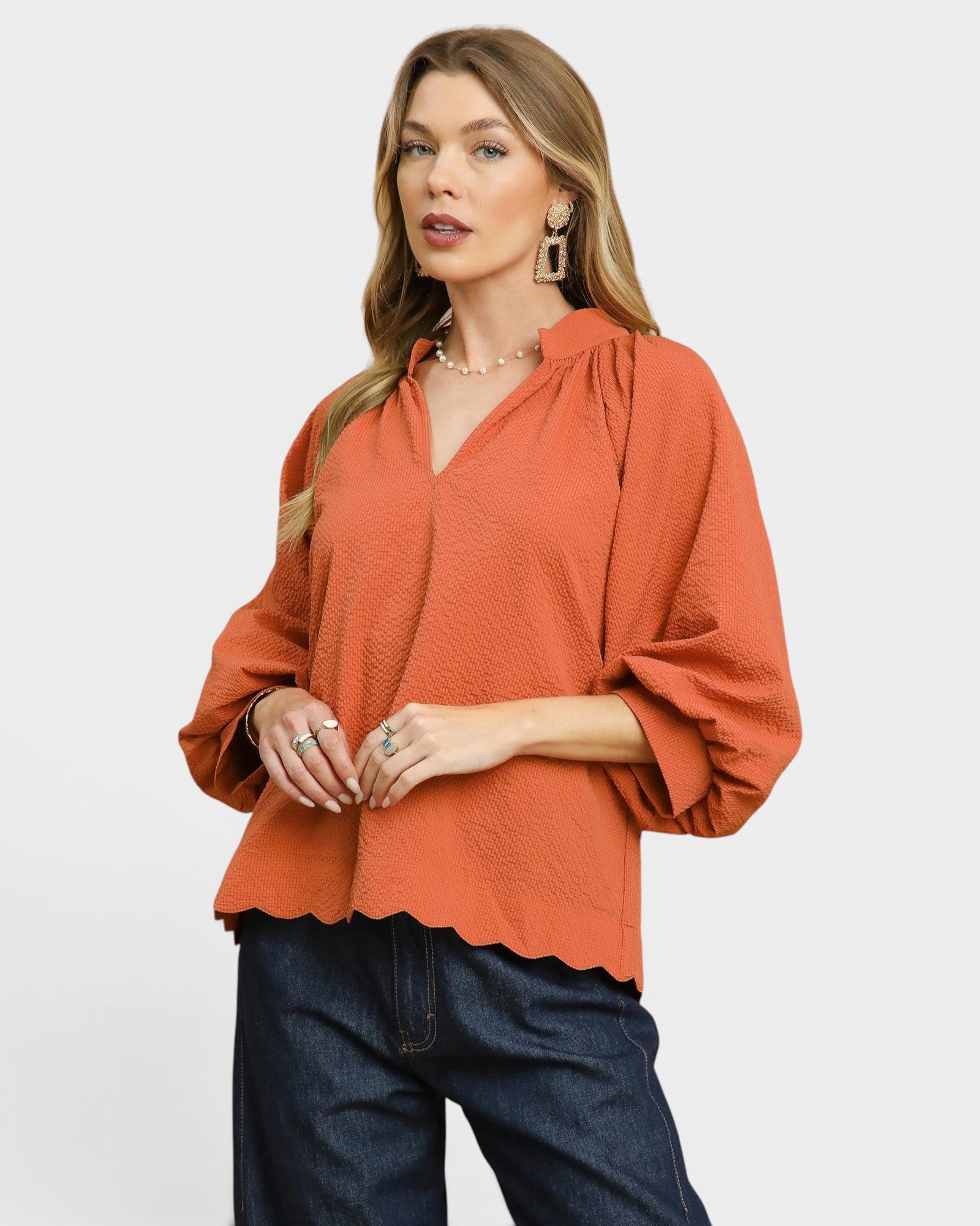 Woman wearing an orange blouse with a plain background