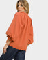 Woman wearing an orange textured blouse with a white background