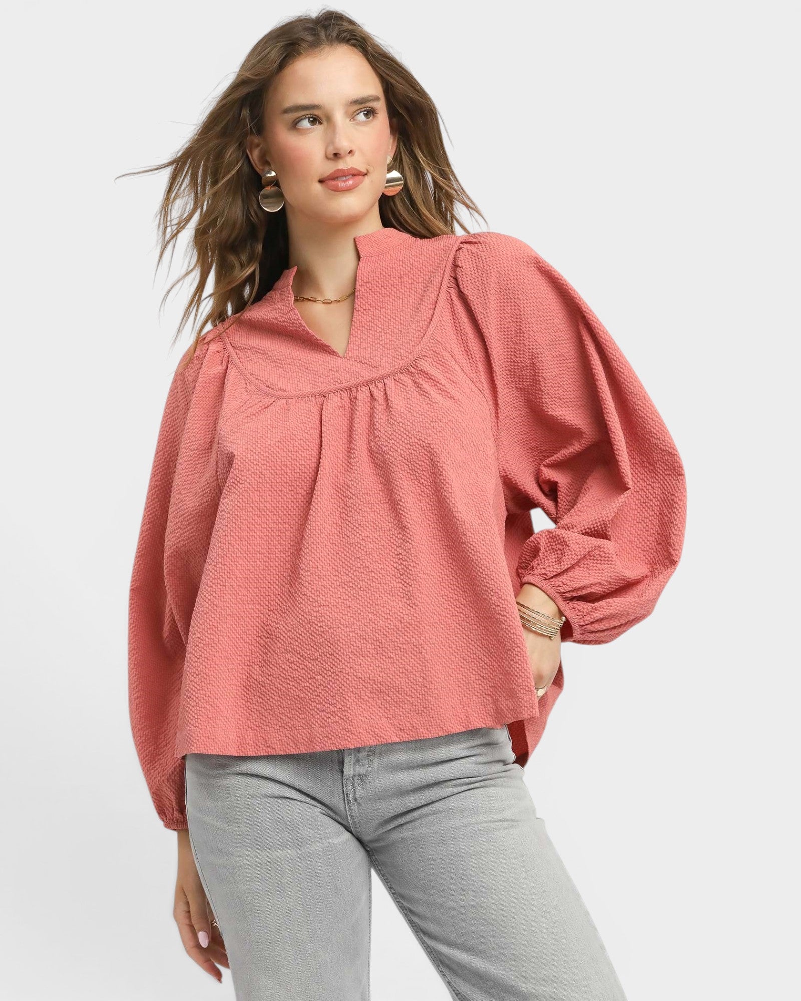 Woman wearing a pink blouse with long sleeves on a white background