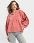 Woman wearing a pink blouse with long sleeves on a white background