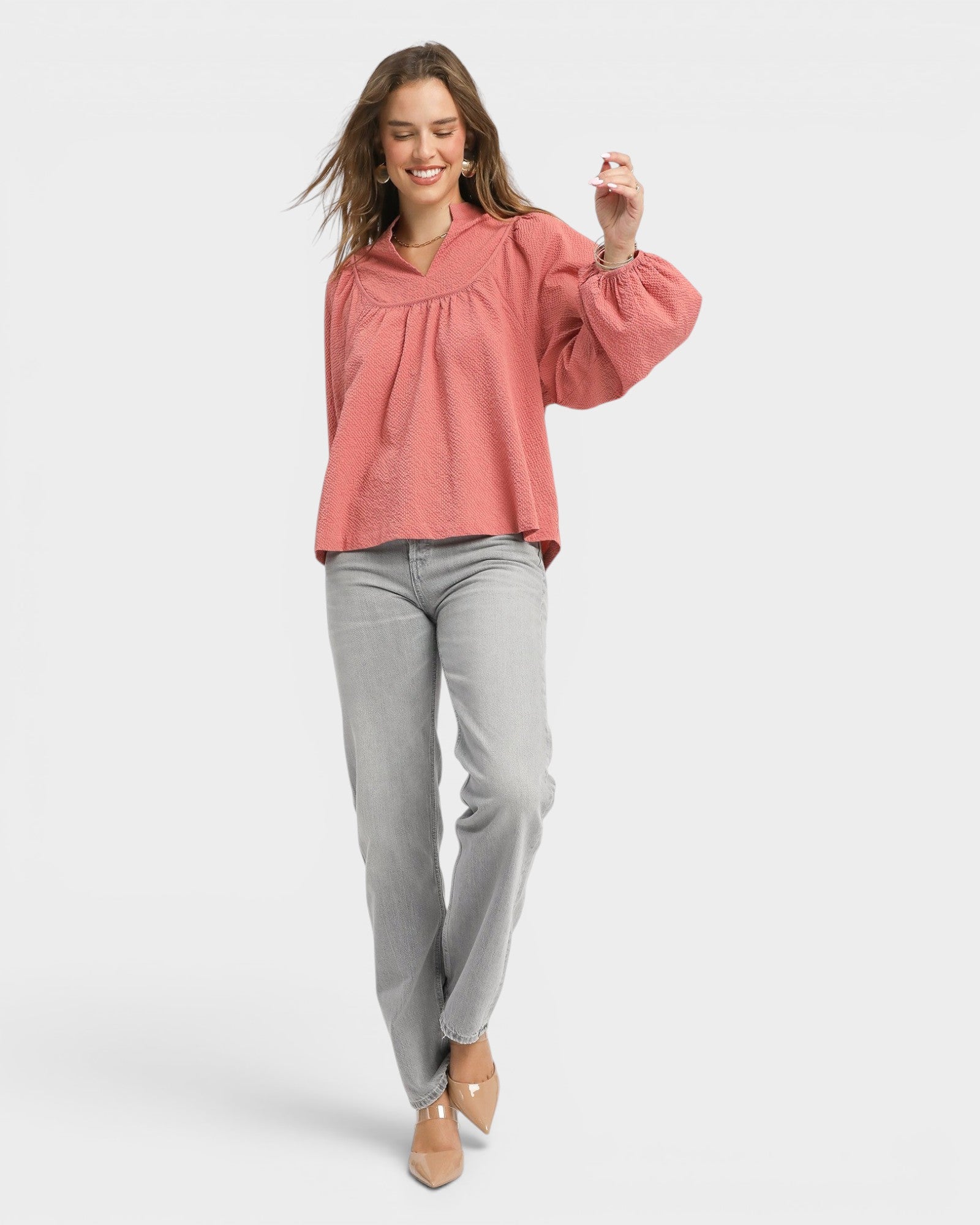 Woman wearing a pink blouse and gray pants on a white background