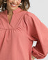 Woman wearing a pink blouse with puffed sleeves on a white background