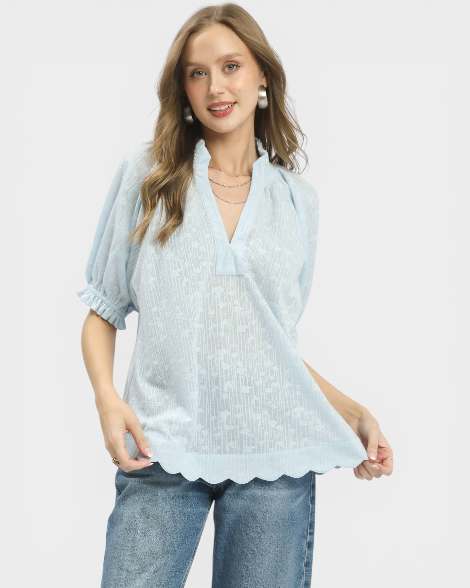 Woman wearing a light blue blouse with a plain background