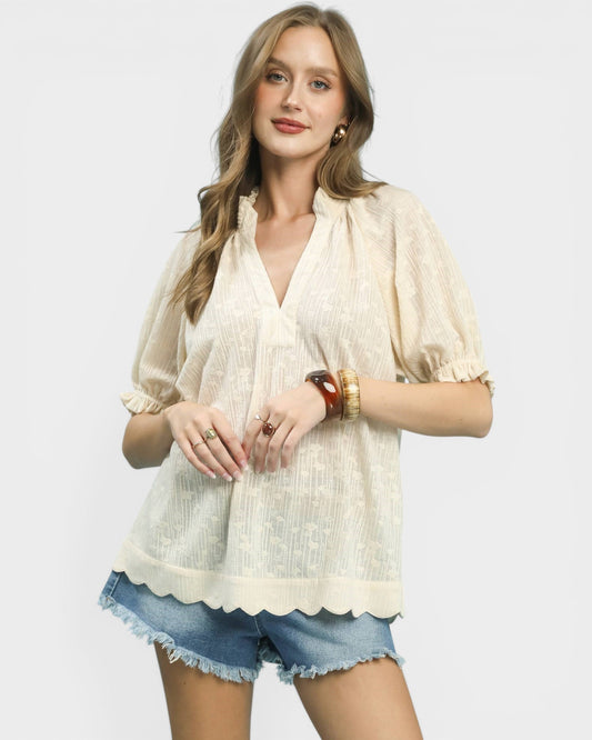 Woman wearing a light-colored blouse and denim shorts on a white background