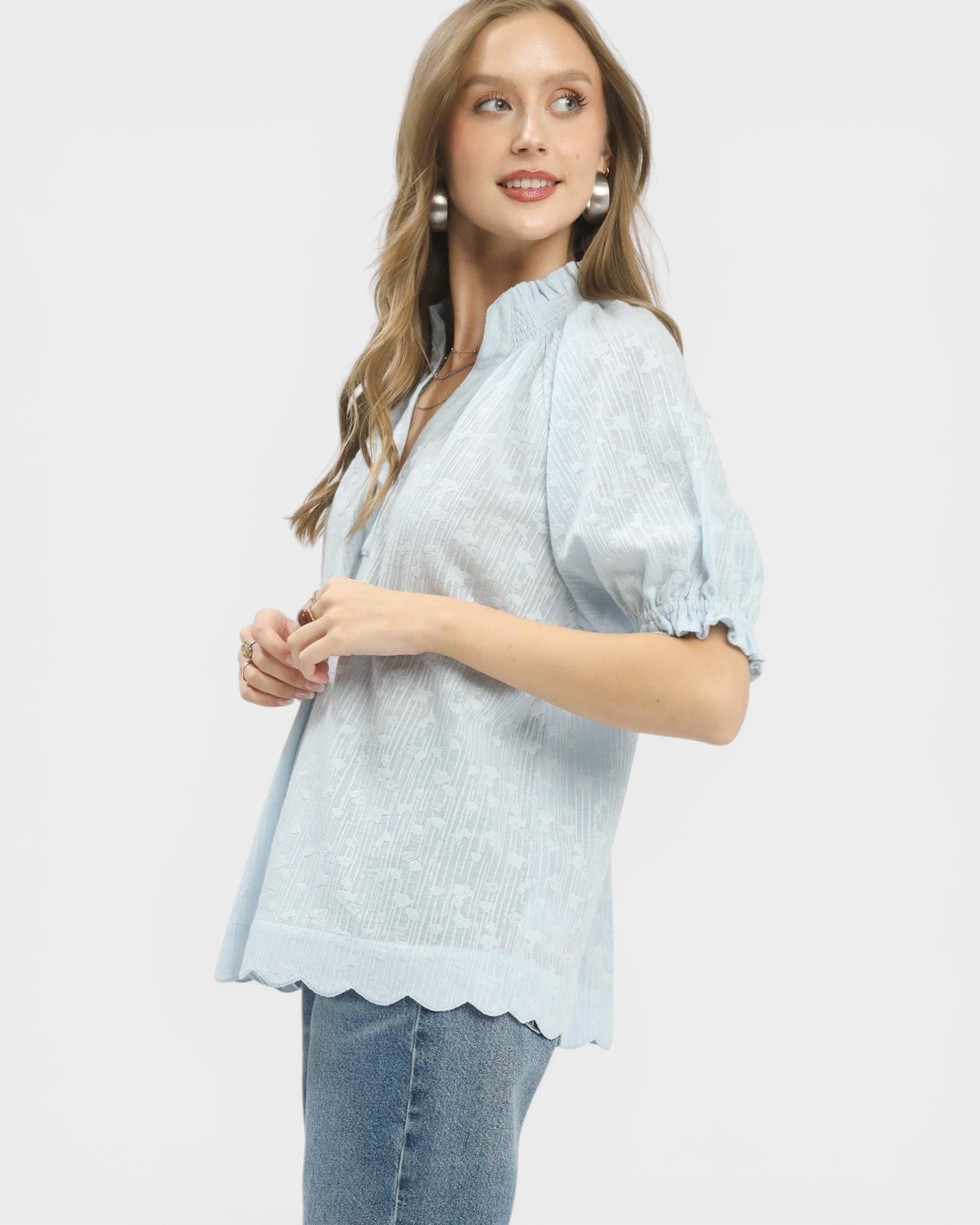 Woman wearing a light blue blouse with ruffled sleeves on a white background