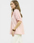 Woman wearing a light pink blouse with ruffled sleeves on a white background