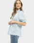 Woman wearing a light blue blouse with ruffled sleeves on a white background