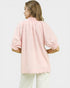 Woman wearing a pink blouse with puffed sleeves on a light gray background