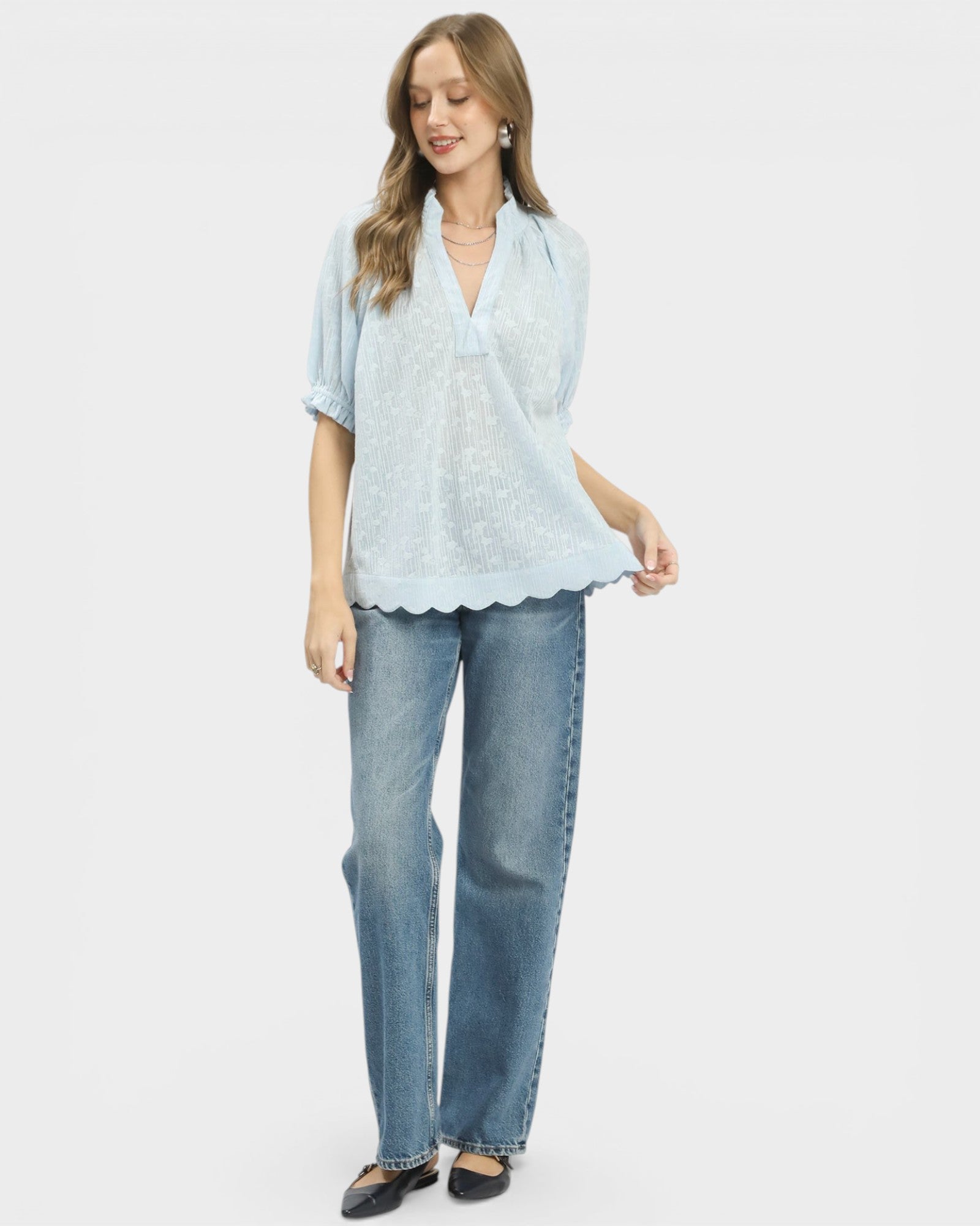 Woman wearing a light blue blouse and jeans on a white background