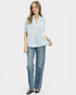 Woman wearing a light blue blouse and jeans on a white background