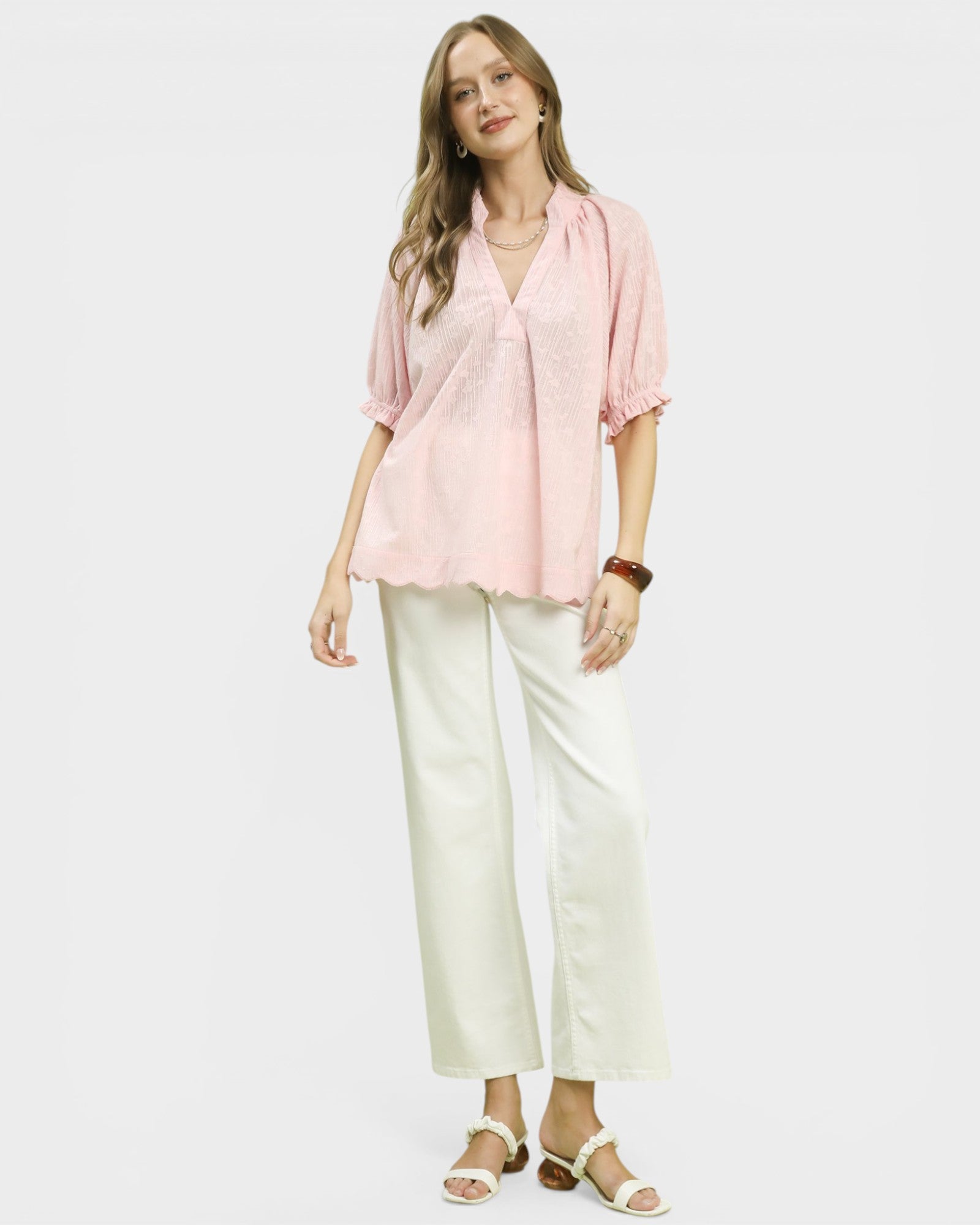 Woman wearing a pink blouse and white pants on a white background