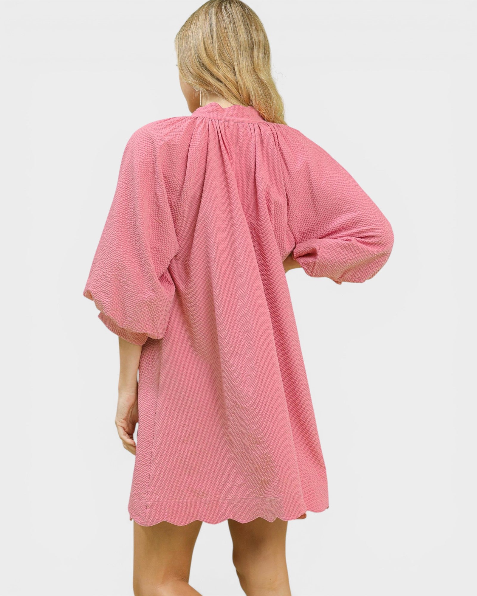 Person wearing a pink textured dress on a white background
