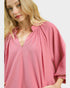Woman wearing a pink textured blouse on a white background