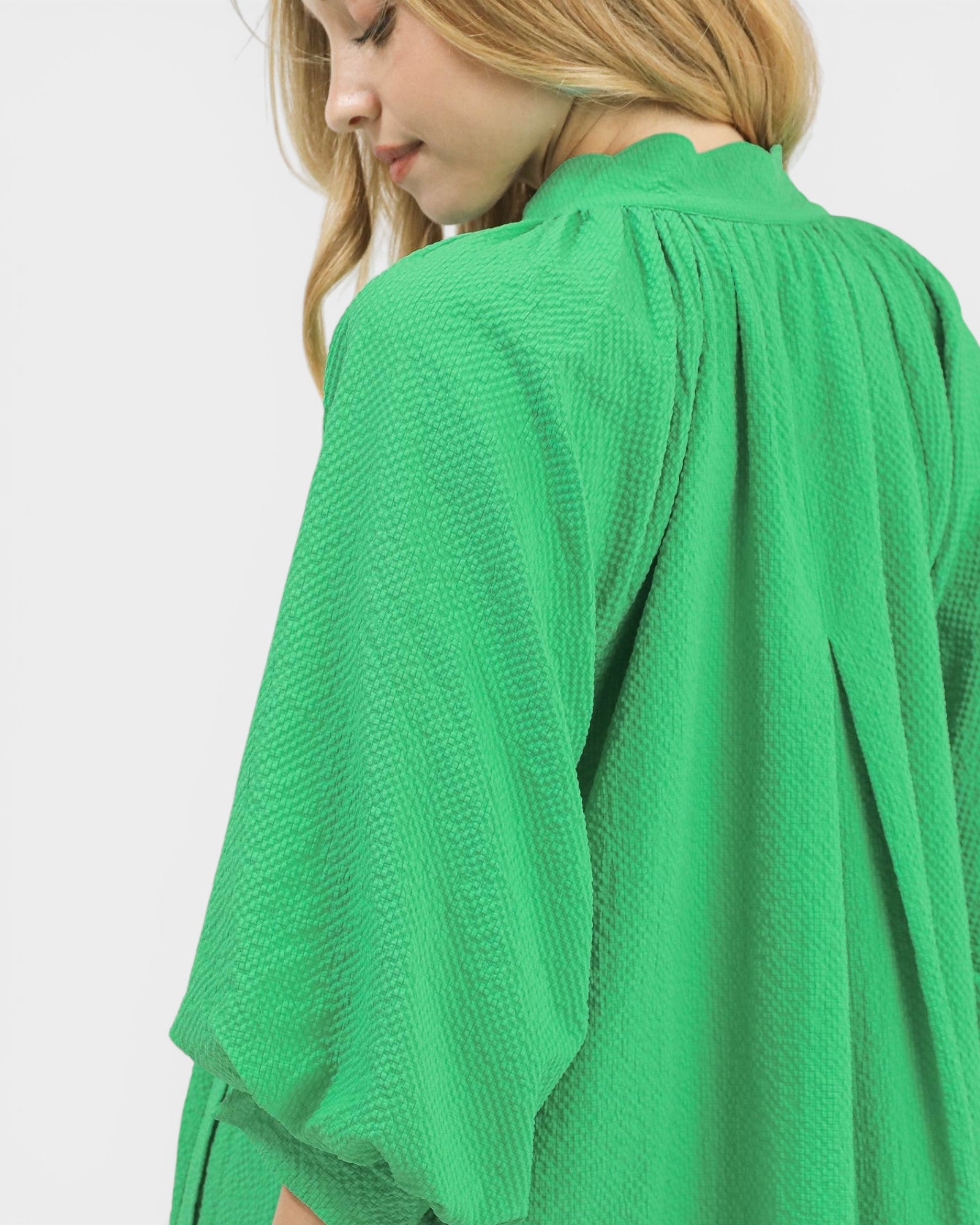 Green textured garment worn by a person on a white background