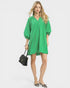 Woman wearing a green dress holding a black handbag on a white background