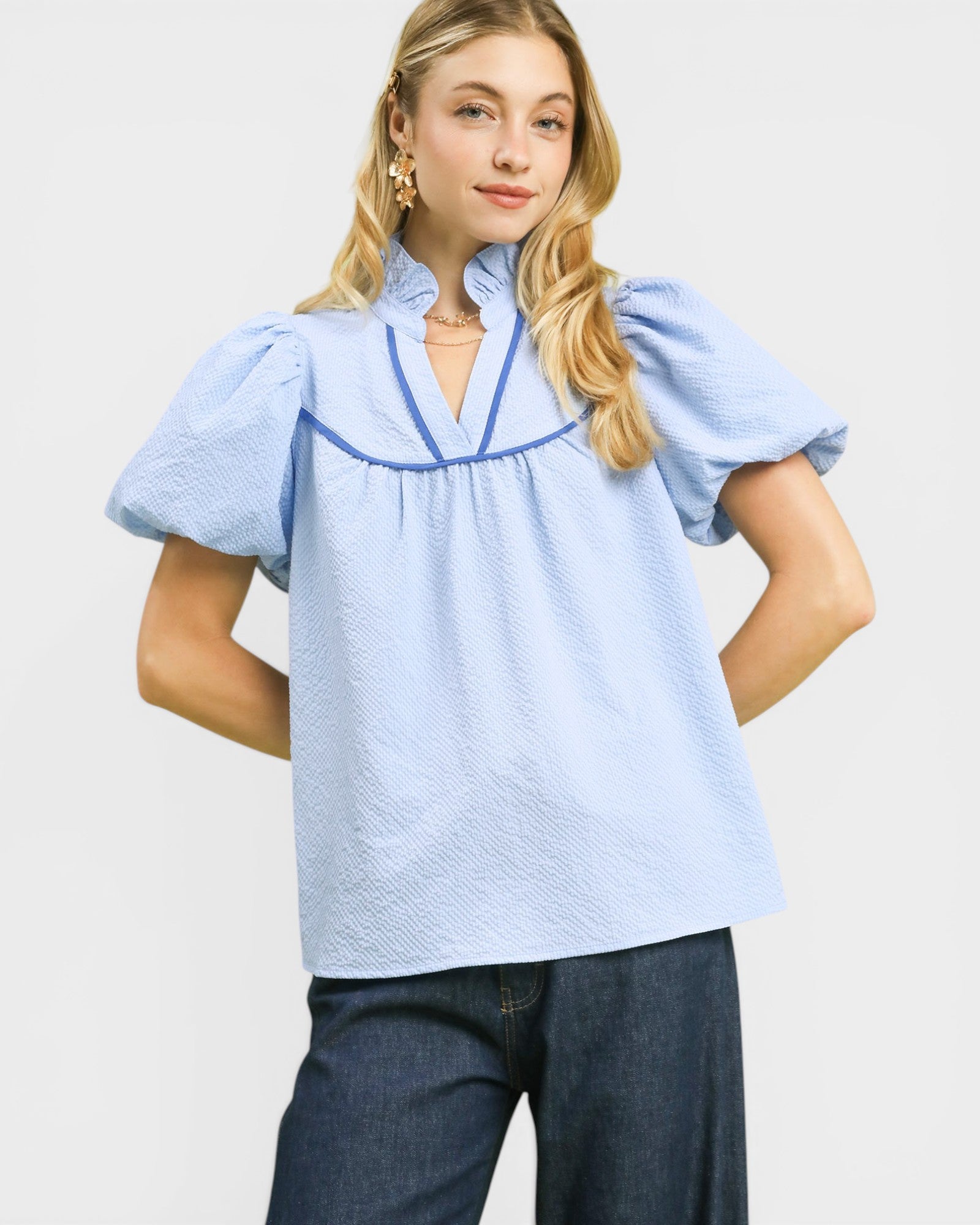 Woman wearing a light blue blouse with short sleeves and a V-neckline on a white background