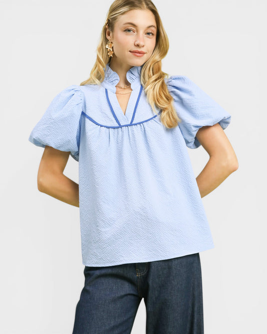 Woman wearing a light blue blouse with short sleeves and a V-neckline on a white background