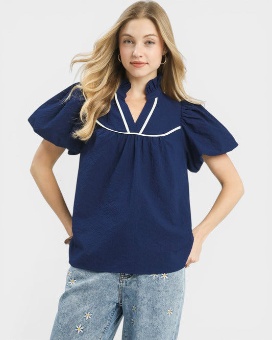 Woman wearing a navy blue blouse with white trim on a white background