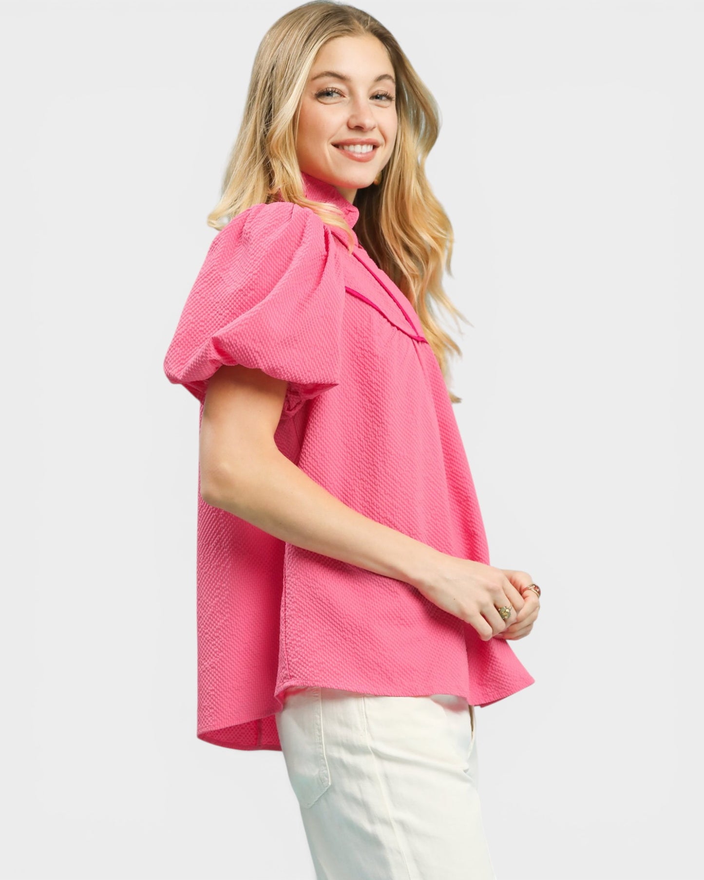 Woman wearing a pink blouse with ruffled sleeves on a white background