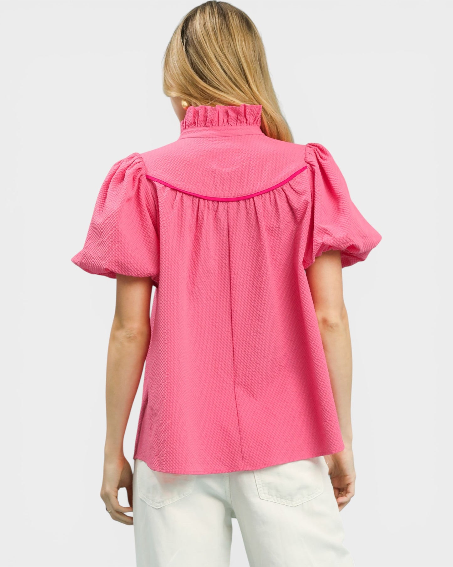 Woman wearing a pink blouse with puff sleeves on a white background