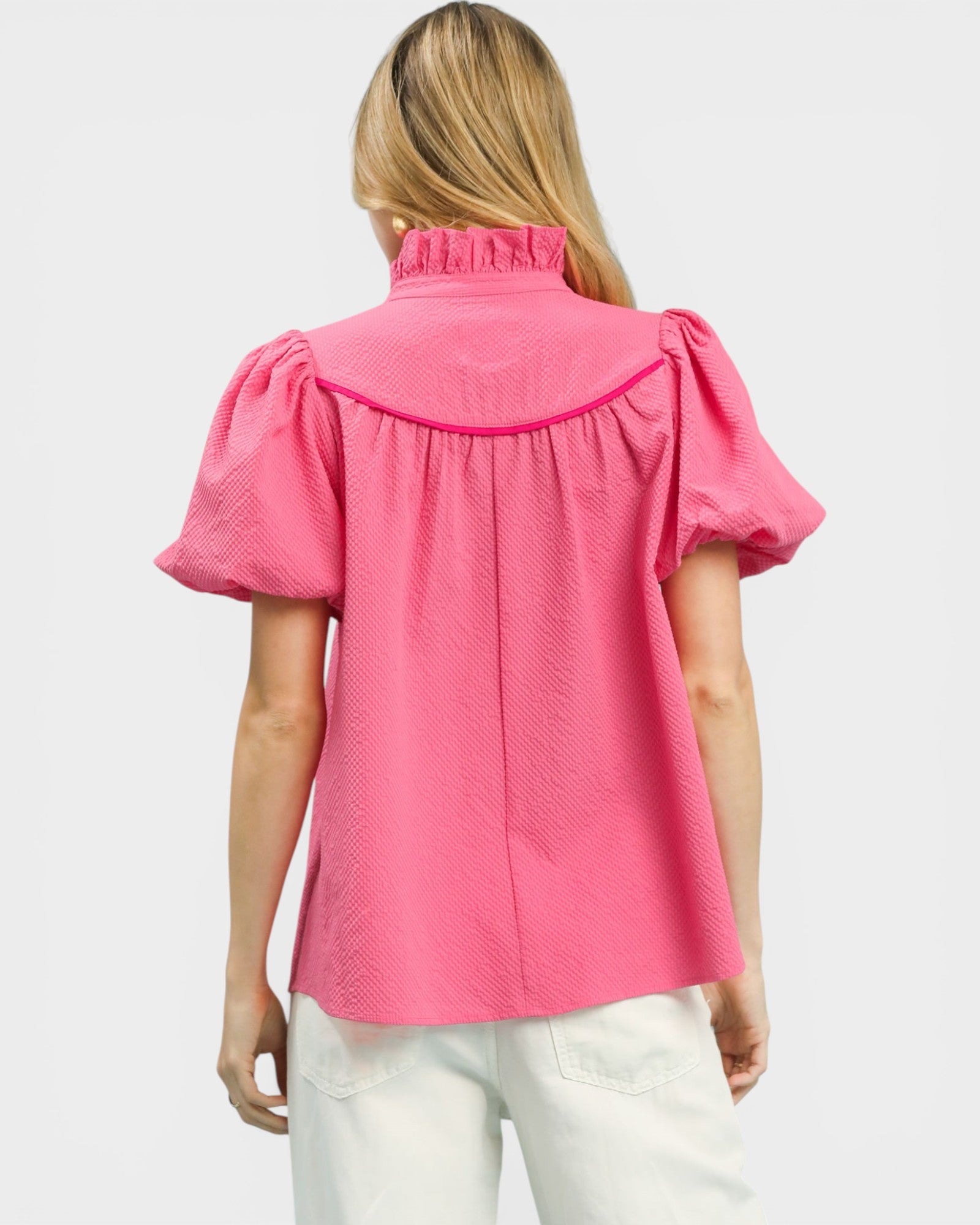Woman wearing a pink blouse with puff sleeves on a white background