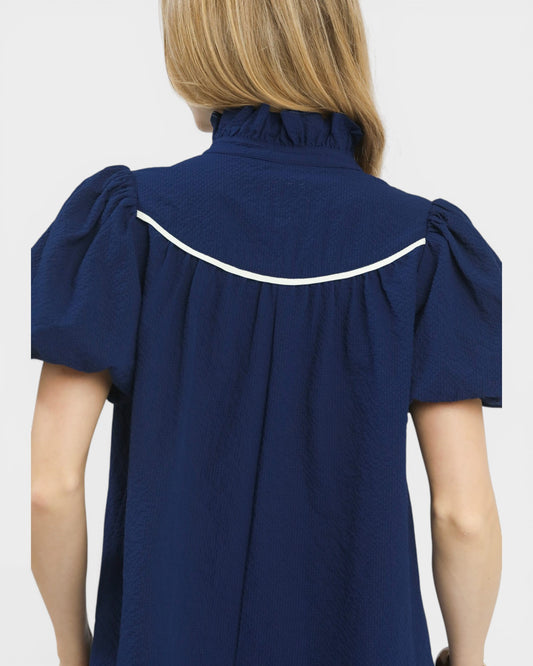 Navy blue blouse with white trim on a plain background