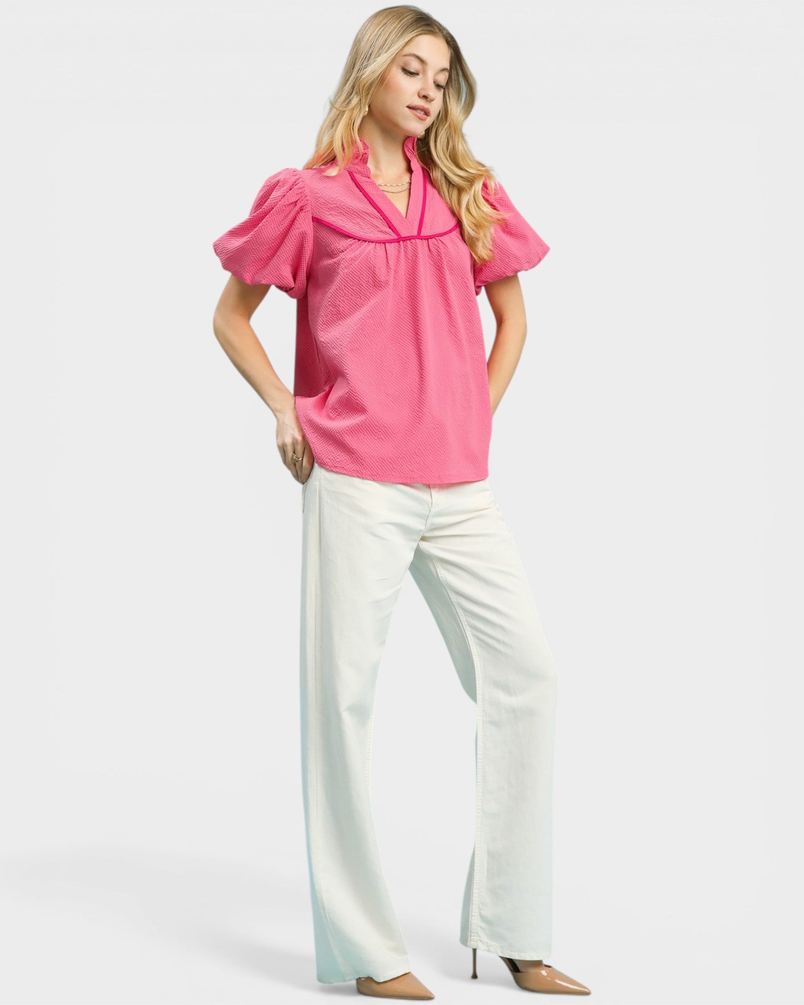 Woman wearing a pink blouse and white pants on a white background