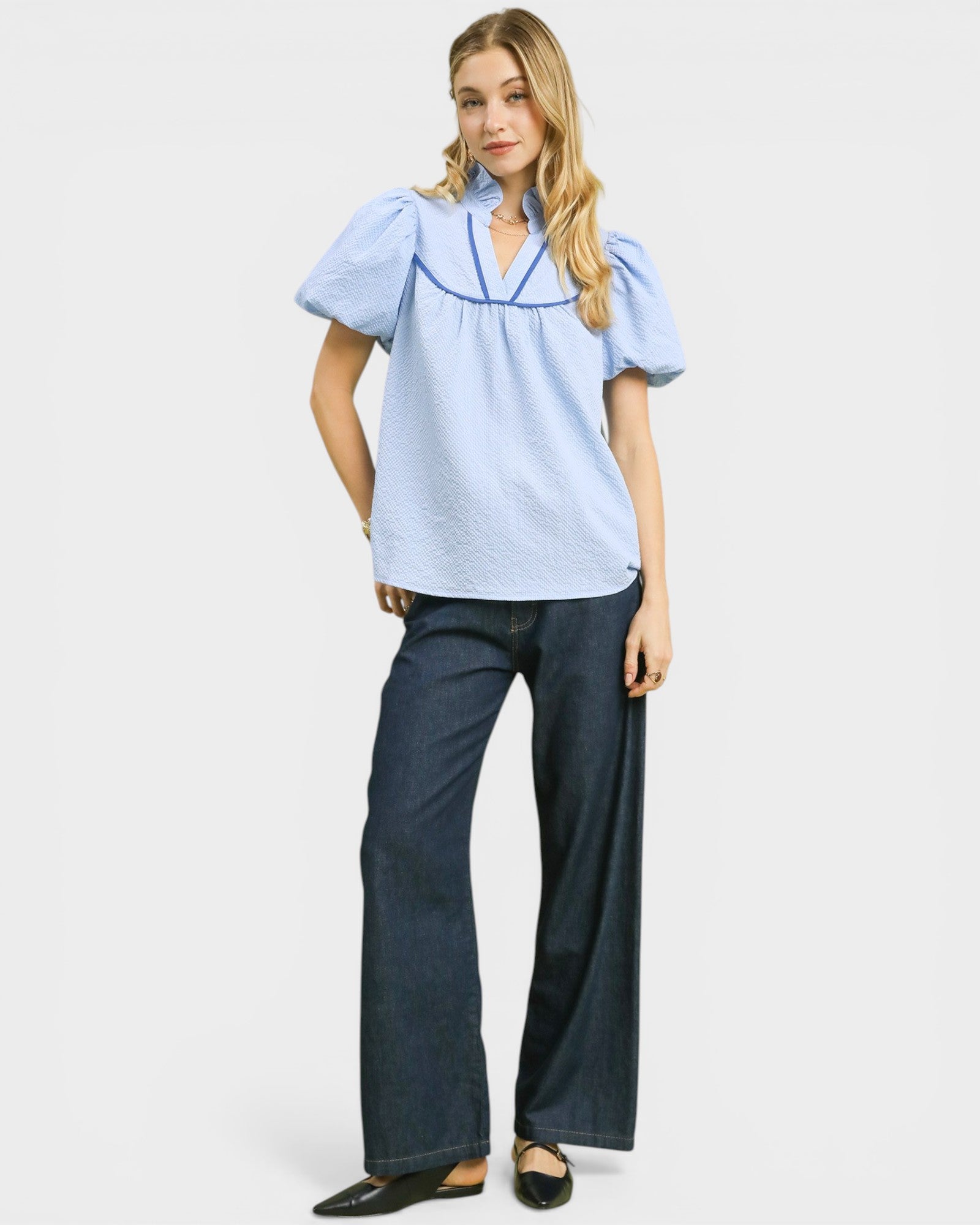 Woman wearing a light blue blouse and dark blue jeans on a white background