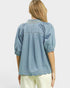 Woman wearing a light blue denim shirt with puffed sleeves on a white background