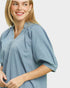 Woman wearing a light blue blouse with short sleeves on a plain background