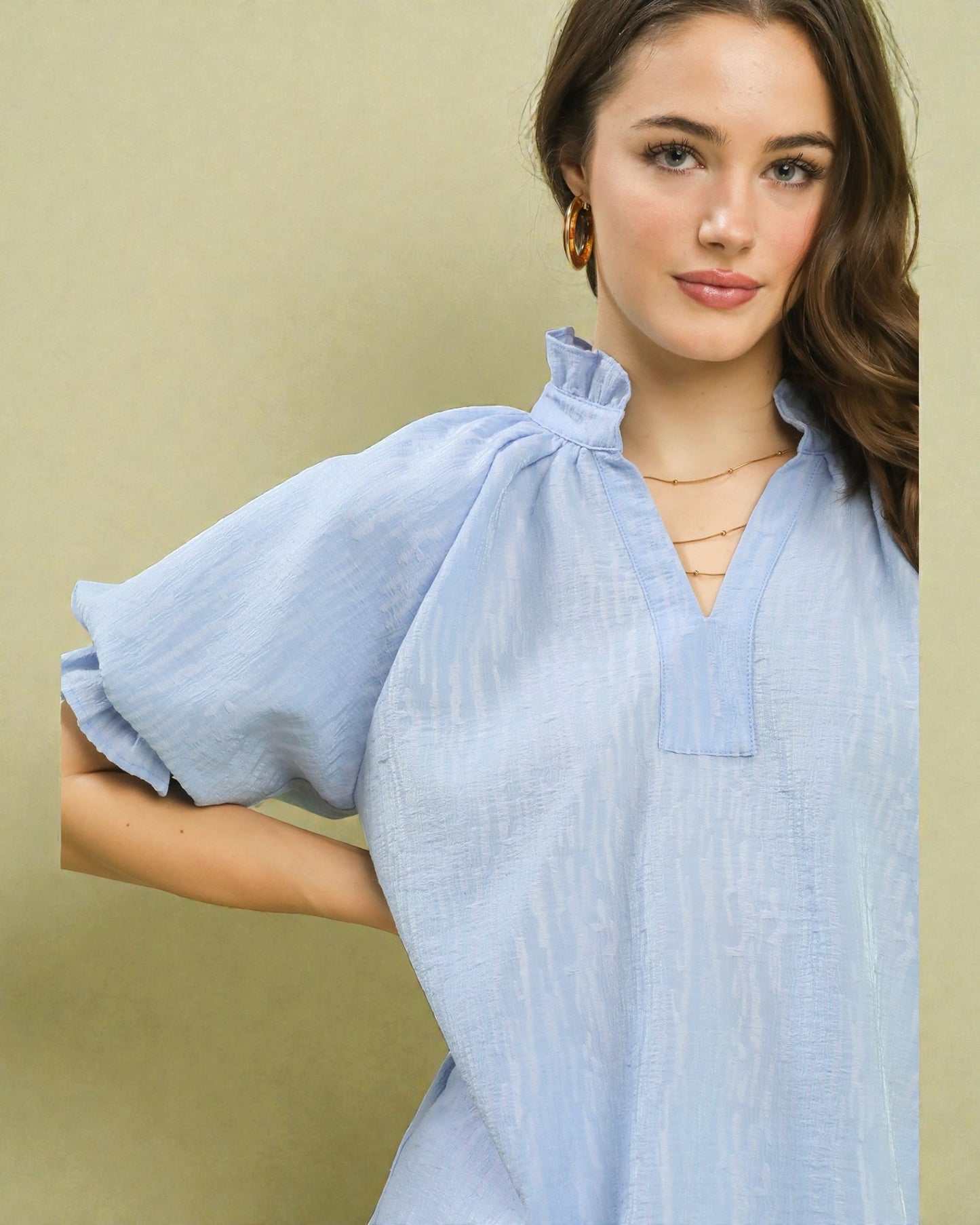 Woman wearing a light blue top against a beige background